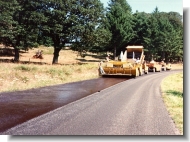 Chip seal spreader applying oil to roadway